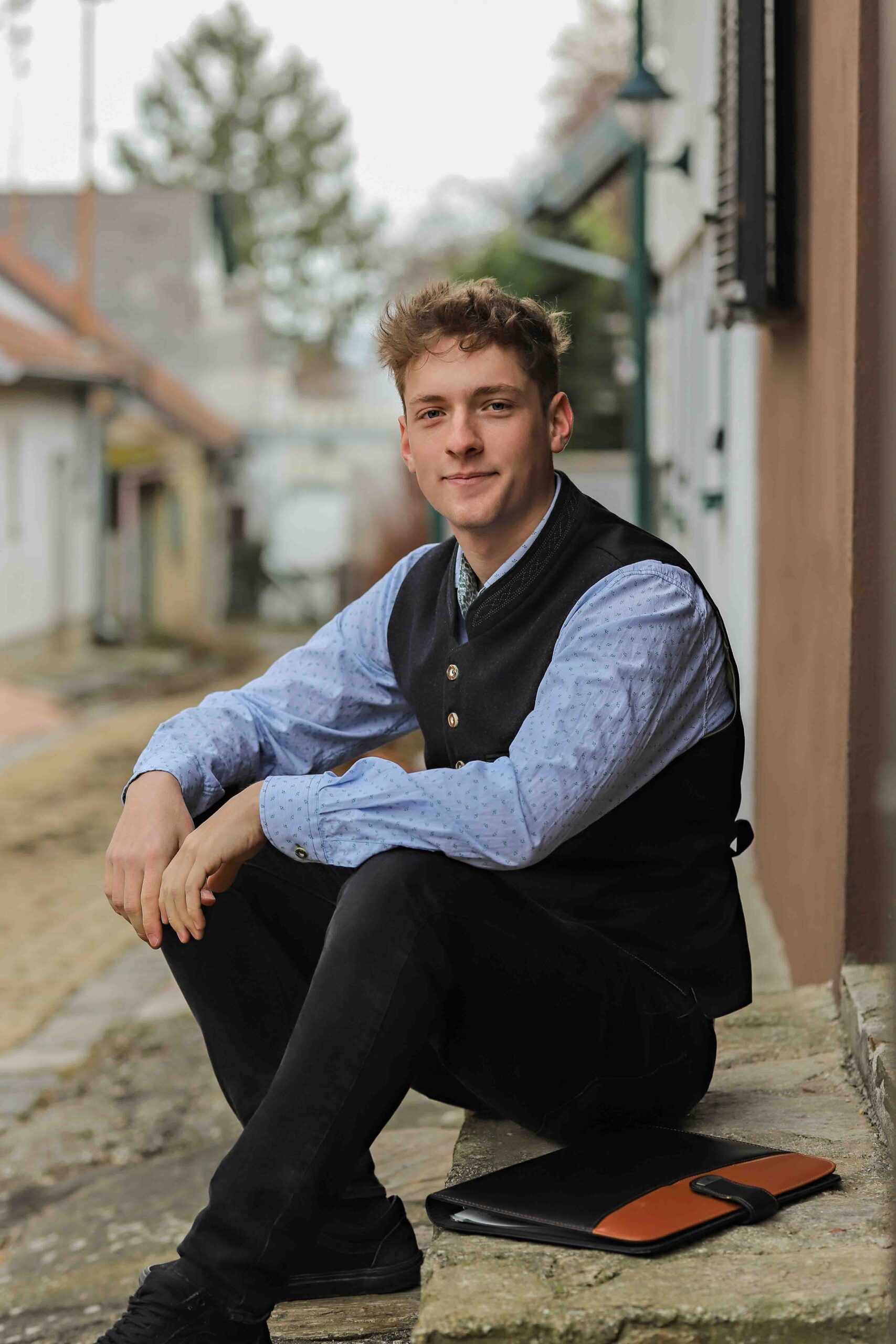 Portraitfoto von Fabian Brauchart - er sitzt am Boden und blickt in Richtung Kamera - über uns